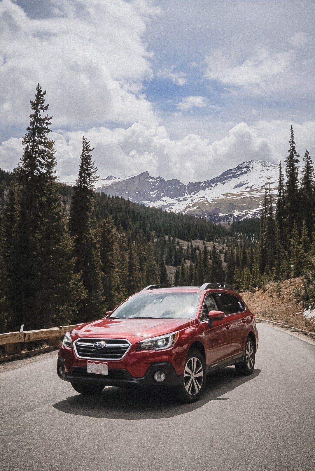 Red Subaru Outback driving a mountain road in Colorado