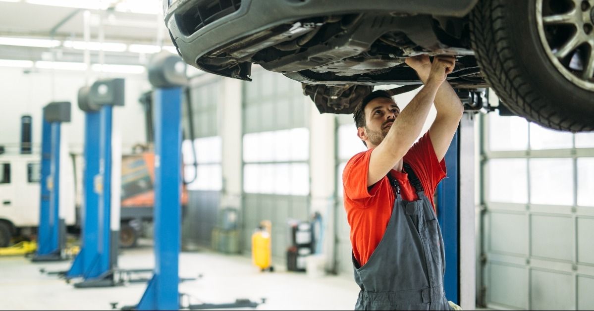 Automotive technician working beneath a vehicle on a lift
